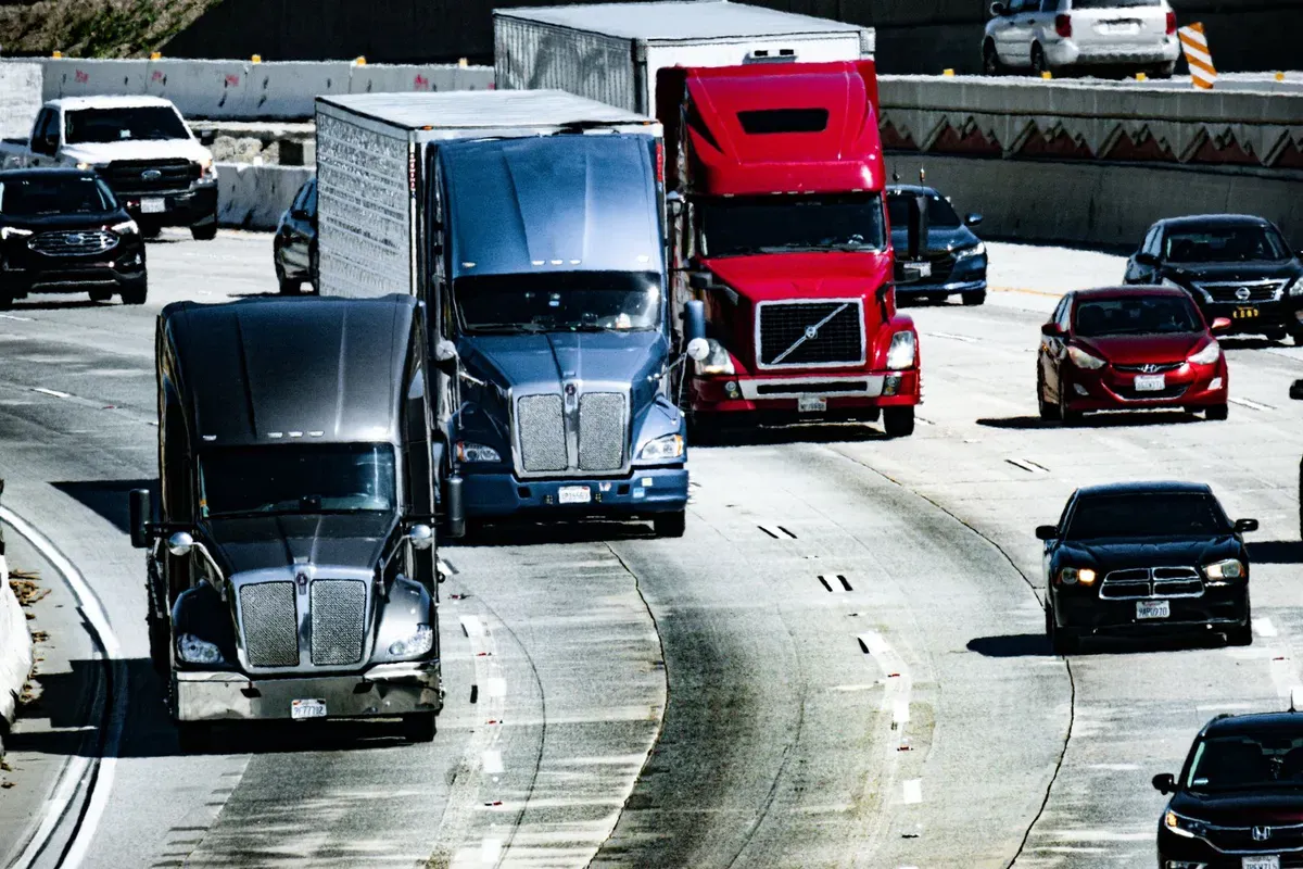 Trucks sharing a congested highway — gateway queues and approach-road congestion drive real transit time