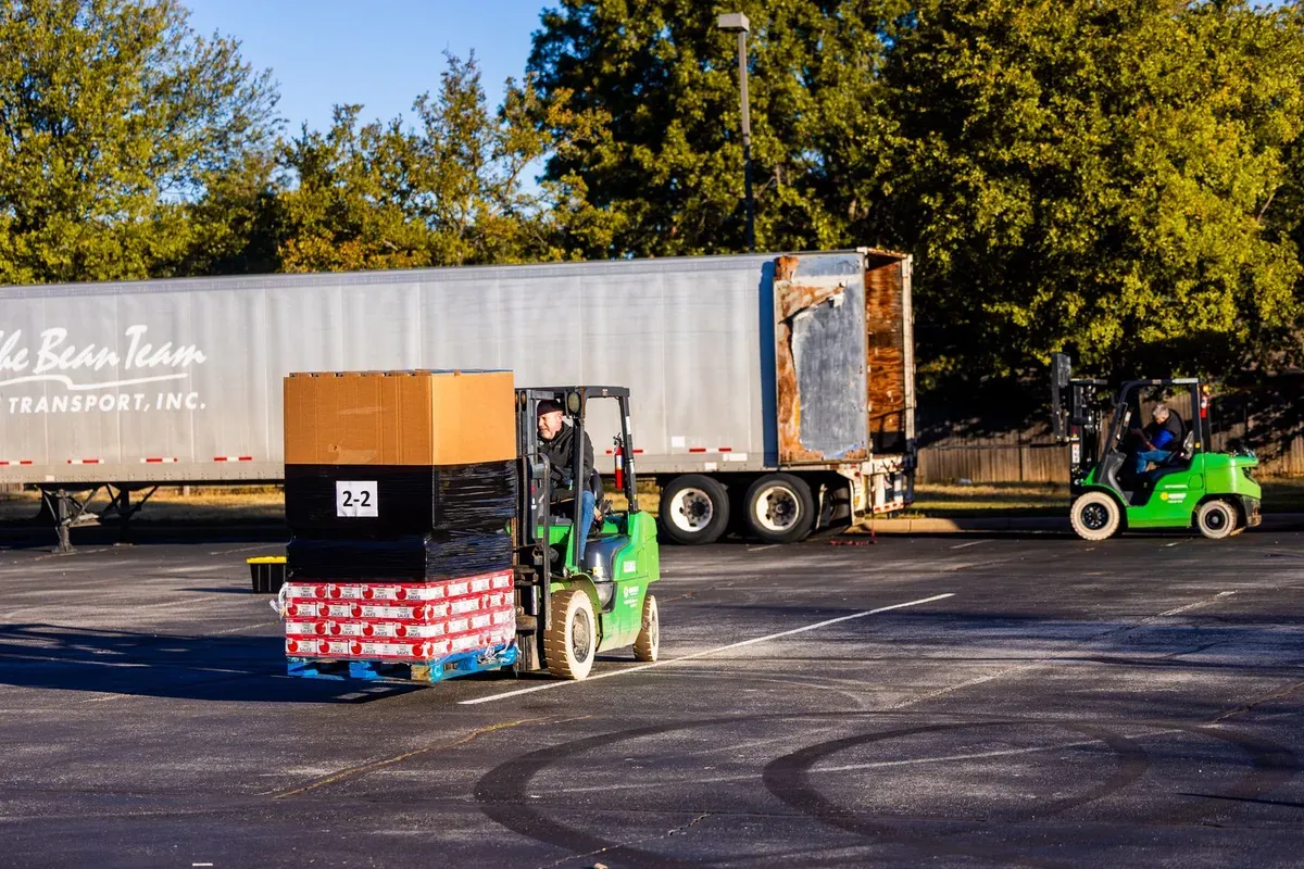 Forklift operators loading pallets onto a truck at a warehouse loading dock