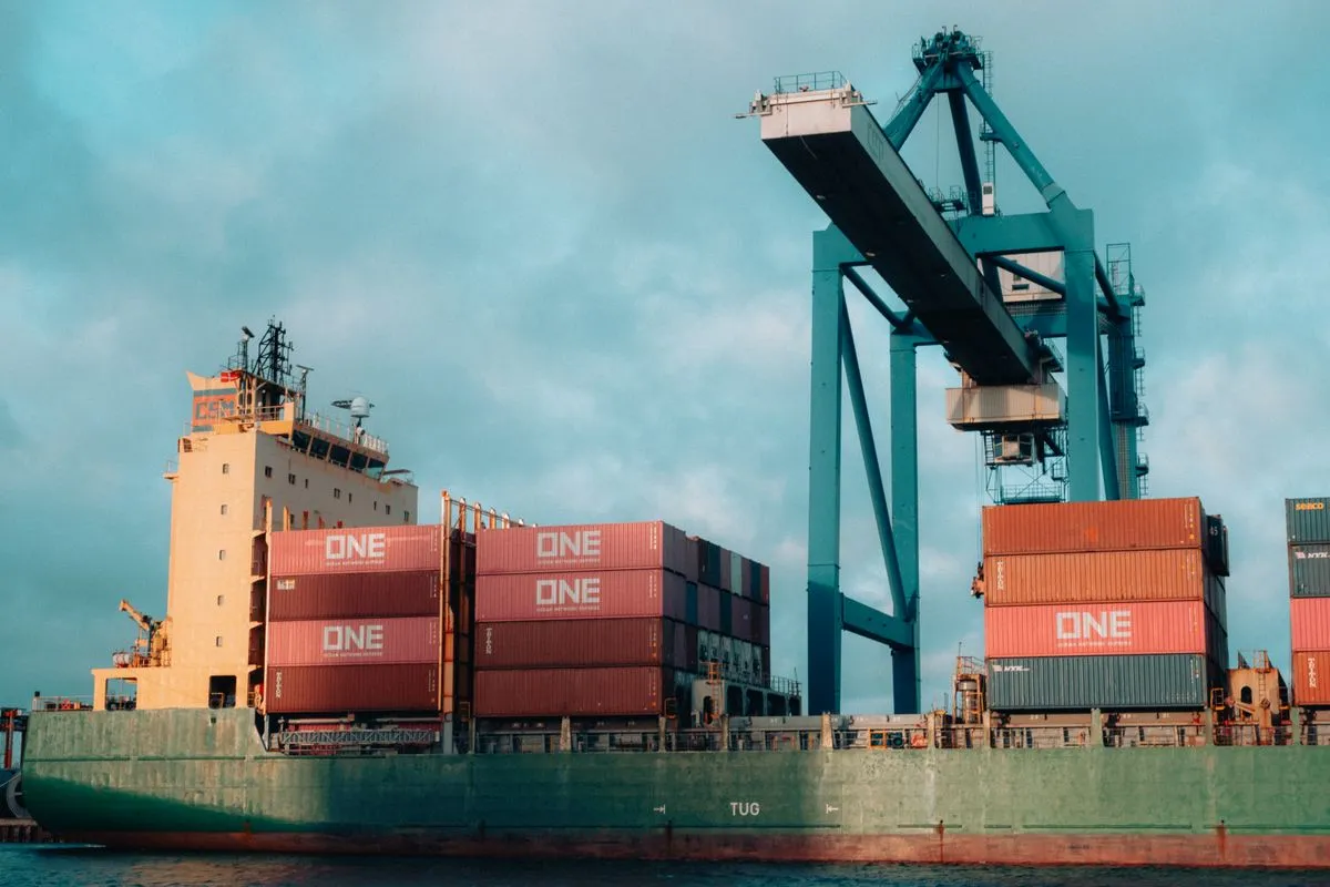 Large container cargo ship docked at an industrial port with cranes
