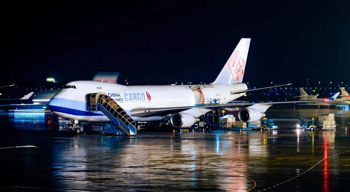Cargo airplane being loaded with freight at an airport at night