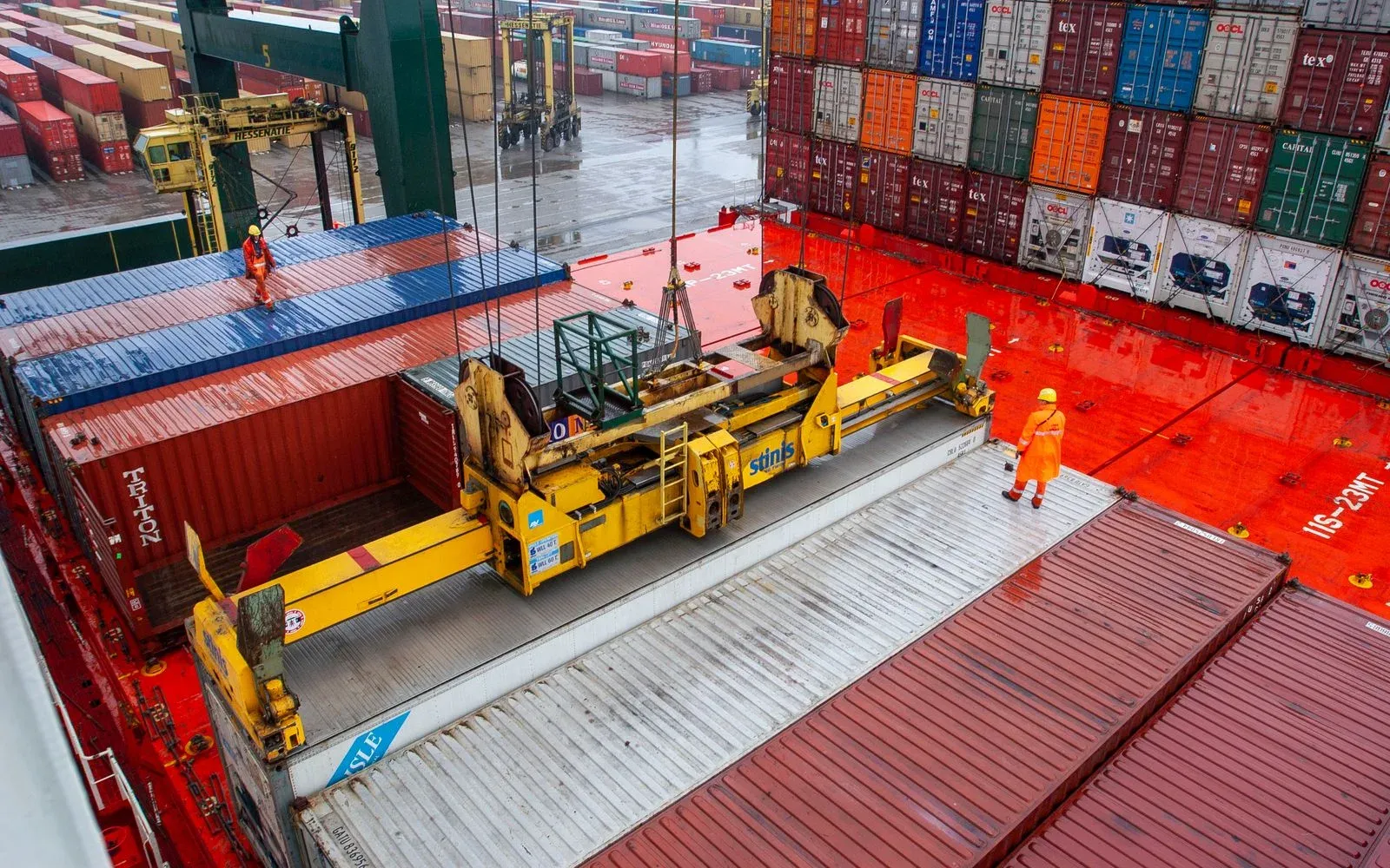 Containers being lifted and lashed on a vessel deck by a gantry crane